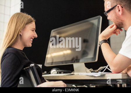 Young businessman and businesswoman looking at computer monitor in creative office Banque D'Images