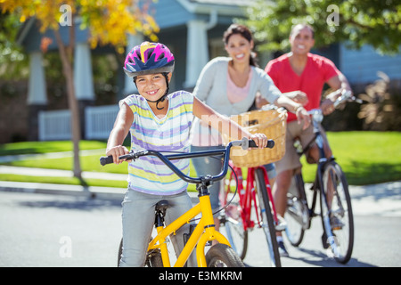 Portrait of smiling family riding bikes in street Banque D'Images