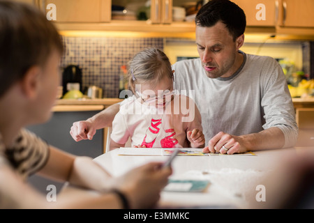 Enseignement Père fille avec fils en premier plan à la maison Banque D'Images