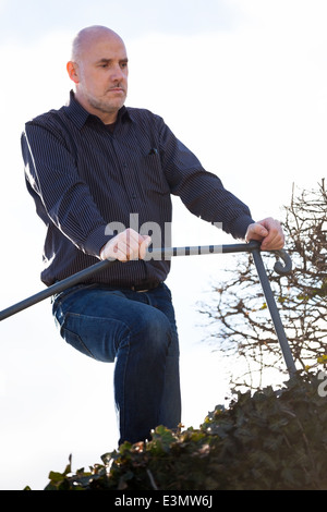Vue de dessous d'un homme d'âge moyen assis sur une volée de marches dans la distance avec une expression grave Banque D'Images
