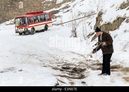 Réglage de l'homme branches sur la route pour aider un bus passant sur un patch sur la route glissante, l'Arménie Banque D'Images