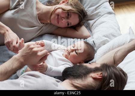 Les parents affectueux regardant baby girl tout en vous relaxant sur le matelas Banque D'Images