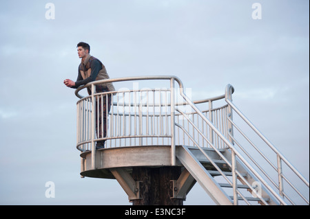 La longueur totale de l'homme réfléchi à la tour leaning on railing Banque D'Images