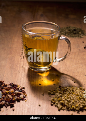 Passoire du thé dans la tasse avec des herbes sur la table Banque D'Images