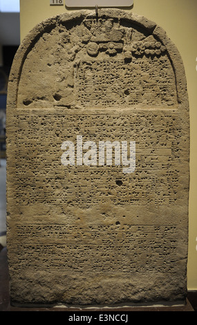 Stèle du roi avec l'inscription et d'un relief représentant le roi Sanchérib priant devant les symboles divins. La pierre calcaire. Banque D'Images