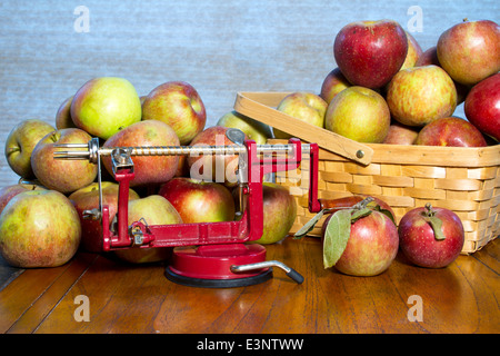 Old fashioned apple peeler carottier et sur une table en bois entourée de pommes Banque D'Images