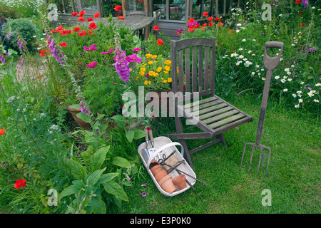 Joli jardin de fleurs et jardin avec siège et met en œuvre des trug Banque D'Images