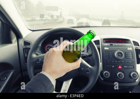 Homme avec une bouteille de bière au volant d'un véhicule Banque D'Images