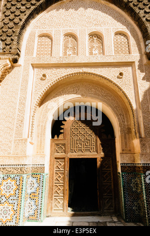 Les carreaux de céramique à motifs complexes sur les murs autour d'une porte en bois au Musée de Marrakech, Maroc Banque D'Images