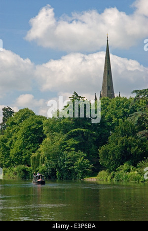 Un petit bateau sur la rivière Avon passe le clocher d'église de l'église Holy Trinity, lieu de sépulture de la dramaturge William Shakespeare. Banque D'Images