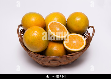 Un panier en osier avec des oranges sur fond blanc / Fruits Banque D'Images
