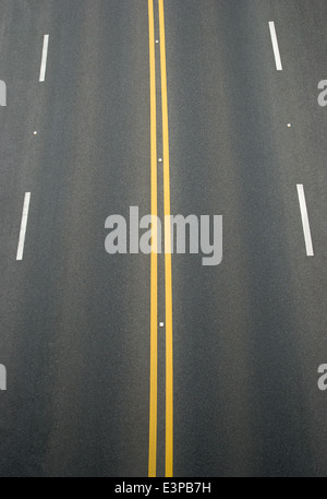 Double yellow lines et lignes blanches sur diviseur blacktop Banque D'Images