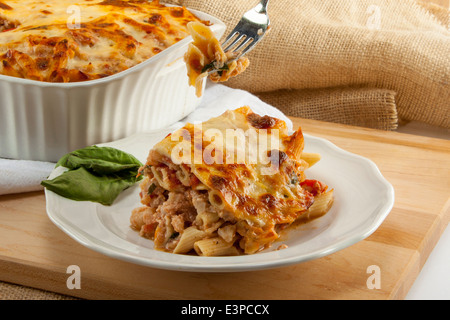 Ziti cuit italien servant sur la plaque avec un cocotte en arrière-plan. Fourche de morsure sur elle. Ressemble à des lasagnes Banque D'Images