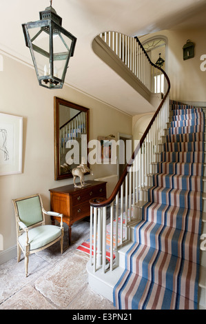 Striped Christine van der Hurd runner sur escalier avec rampe en bois dalle en hall d'entrée avec un fauteuil Banque D'Images