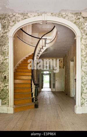 Escalier elliptique dans le couloir avec arch, décollement du papier peint à motifs et voir jusqu'à l'entrée arrière Banque D'Images