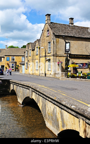 Passerelle en pierre de l'autre côté de la rivière Windrush avec l'Kingsbridge Inn à l'arrière, Bourton On The Water, England, UK. Banque D'Images