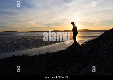Femme marche le long de la côte de Silverdale au coucher du soleil, la baie de Morecambe, Lancashire, England UK Banque D'Images
