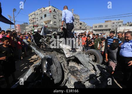 La bande de Gaza. 27 Juin, 2014. Les Palestiniens se retrouvent autour d'une voiture qui a été la cible d'une attaque aérienne israélienne à Gaza le 27 juin 2014. Deux militants palestiniens ont été tués vendredi comme un jet de guerre israéliens ont frappé leur véhicule en plage Shatti () camp de réfugiés dans l'ouest de la ville de Gaza, selon des témoins et des médecins. © Wissam Nassar/Xinhua/Alamy Live News Banque D'Images