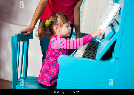 Petite fille joue le piano bleu Banque D'Images