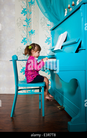 Petite fille joue le piano bleu Banque D'Images