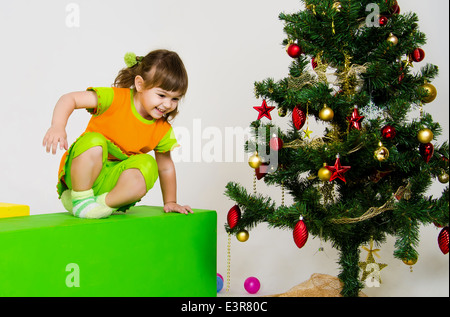 Cute little woman est le jeu près de l'arbre de Noël à l'intérieur Banque D'Images