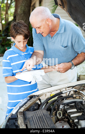 L'enseignement du père, son fils comment vérifier l'huile sur la voiture familiale. Banque D'Images