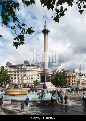 La colonne Nelson et de fontaines, Trafalgar Square, Londres par temps humide avec des nuages gris foncé et les touristes Banque D'Images