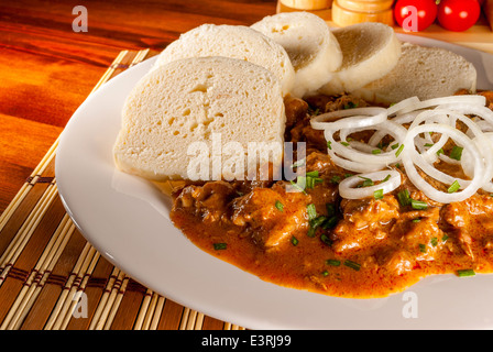 République tchèque traditionnel goulasch avec boulette panée et l'oignon sur plaque blanche sur table en bois Banque D'Images