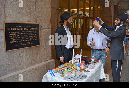 Les Juifs hassidiques Loubavitch encourager un passant pour mettre sur phylactères et dire une prière. L'extérieur de la gare Grand Central à New York Banque D'Images