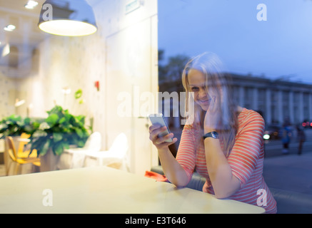 Smiling woman in cafe lecture ou saisie sms Banque D'Images