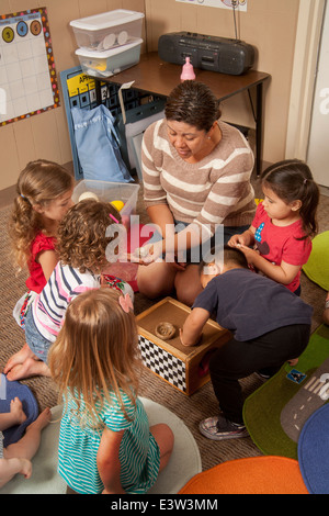 Un enseignant montre hispaniques des nids d'oiseau pour les jeunes enfants à l'apprentissage d'un 'lien' en classe Tustin, CA, à réaliser un atelier interactif dans le comportement. À l'aide d'activités spécialement conçues, la classe enseigne aux parents comment faire participer leurs enfants à jouer utile. Notez dans la case des œufs artificiels. Banque D'Images