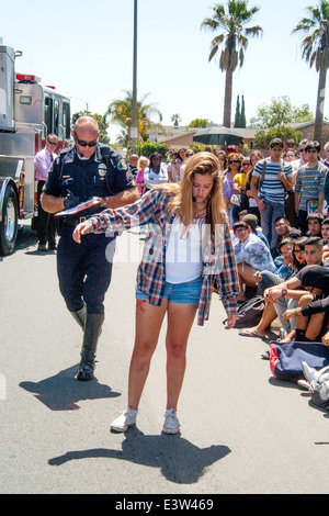 Un bénévole high school girl joue le rôle d'un pilote d'être interrogé par un policier dans une dramatisation du danger de l'alcool au volant à Anaheim, CA, qu'il fait sa promenade pour tester son niveau d'intoxication. Remarque L'auditoire étudiant multiraciale en arrière-plan. Banque D'Images