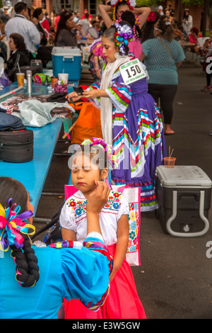 Une fille hispanique en costume mexicain ethnique est constitué par sa mère avant de marcher dans un défilé du jour de l'indépendance mexicaine à San Juan Capistrano, CA. Note marcheur en costume avec le numéro d'identification dans l'arrière-plan. Banque D'Images