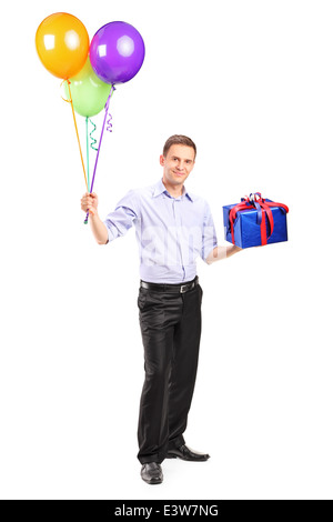 Full Length portrait of a cheerful man holding balloons et un présent Banque D'Images