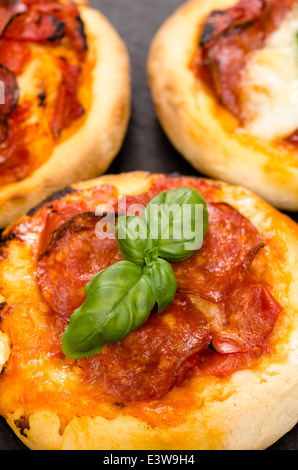 Close up of pizza au salami saucisses et le basilic en format vertical Banque D'Images