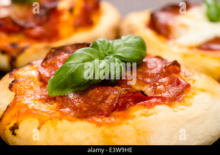 Le basilic sur une pizza italienne avec saucisses chorizo salami Banque D'Images