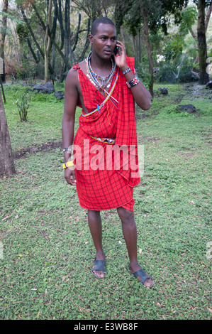 Homme massaï en vêtements traditionnels à l'aide de téléphone mobile dans le Parc national Amboseli Kenya Afrique de l'Est Banque D'Images