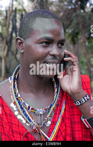 Homme massaï en vêtements traditionnels à l'aide de téléphone mobile dans le Parc national Amboseli Kenya Afrique de l'Est Banque D'Images