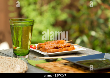 Satay de poulet sur les brochettes sur une plaque carrée blanche à l'extérieur Banque D'Images