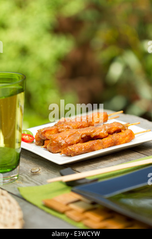 Satay de poulet sur les brochettes sur une plaque carrée blanche à l'extérieur Banque D'Images