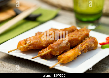 Satay de poulet sur les brochettes sur une plaque carrée blanche à l'extérieur Banque D'Images