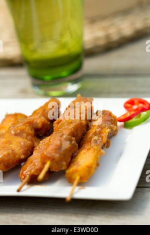 Satay de poulet sur les brochettes sur une plaque carrée blanche à l'extérieur Banque D'Images