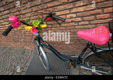 Décorées de fleurs de vélo appuyé contre un mur, Münster, Münster, Rhénanie du Nord-Westphalie, Allemagne Banque D'Images