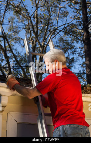 Homme mature Maison nettoyage des gouttières, USA Banque D'Images