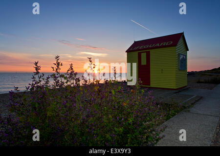 Près de Tankerton Whitstable, Kent, UK 1er juillet 2014 : Le soleil se lève sur une mer calme à proximité d'une cabane de sauveteur comme temps chaud et sec est définie après quelques jours d'averses dans le sud-est. Banque D'Images