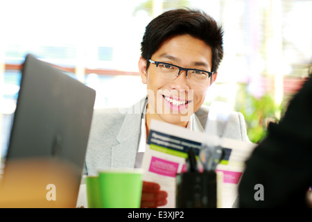 Asian businessman dans les verres à la table in office Banque D'Images