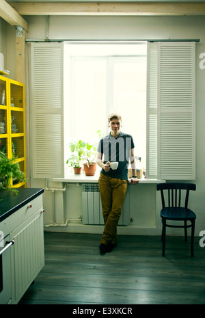 Caucasian man having coffee in kitchen Banque D'Images