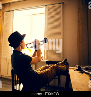 Young man playing Trumpet in kitchen Banque D'Images