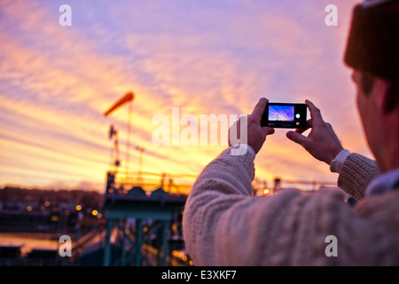 Man taking photo de coucher de soleil sur bridge Banque D'Images