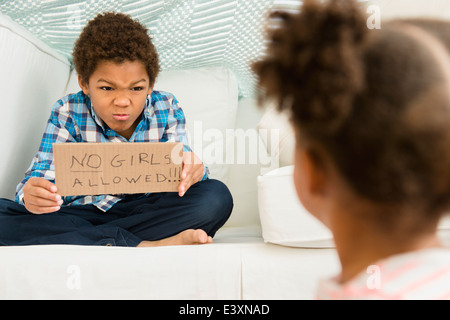 Black Boy holding Pas de filles admis' signe pour sœur Banque D'Images